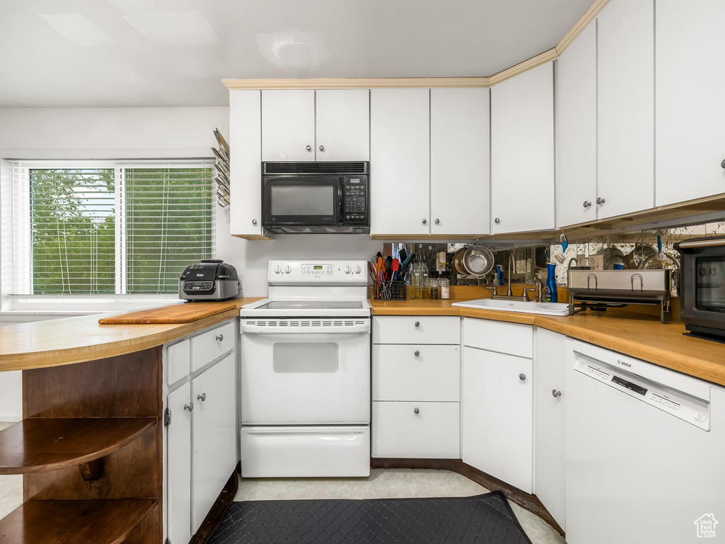 Kitchen featuring white cabinets, white appliances, tasteful backsplash, and sink