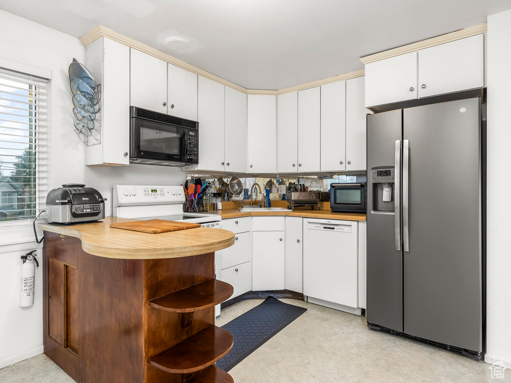 Kitchen with white cabinetry, white appliances, sink, and tasteful backsplash