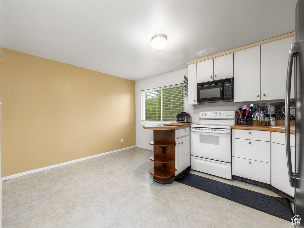 Kitchen featuring electric range, butcher block countertops, and white cabinetry