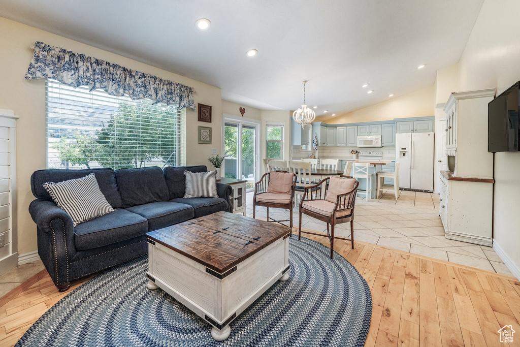 Living room with light hardwood / wood-style flooring, a chandelier, and vaulted ceiling