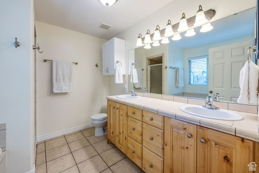 Bathroom featuring vanity, toilet, an enclosed shower, and tile patterned floors