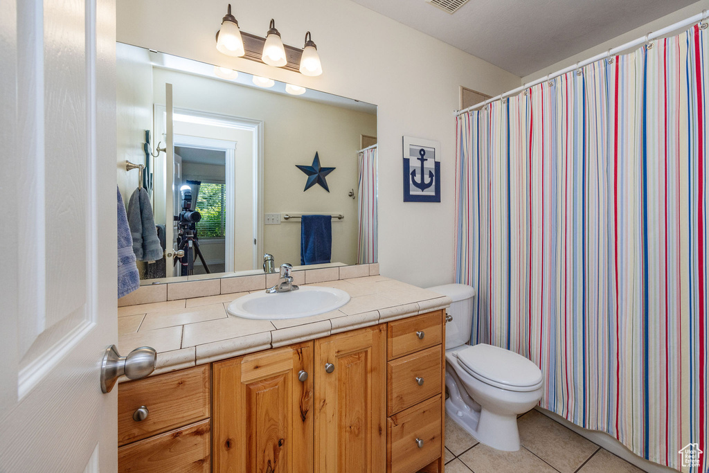 Bathroom with vanity, toilet, and tile patterned floors