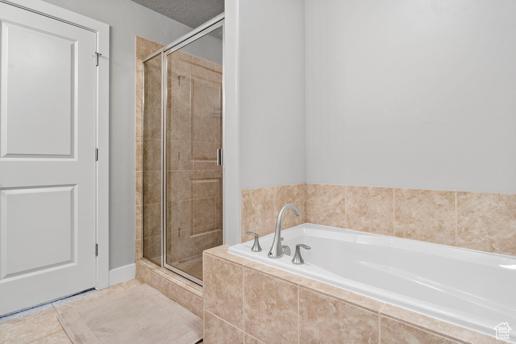 Bathroom with a textured ceiling, tile patterned flooring, and shower with separate bathtub