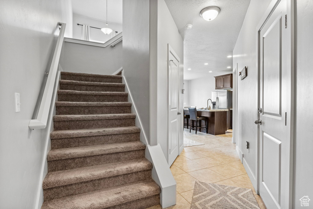 Stairs featuring a textured ceiling, sink, and tile patterned flooring