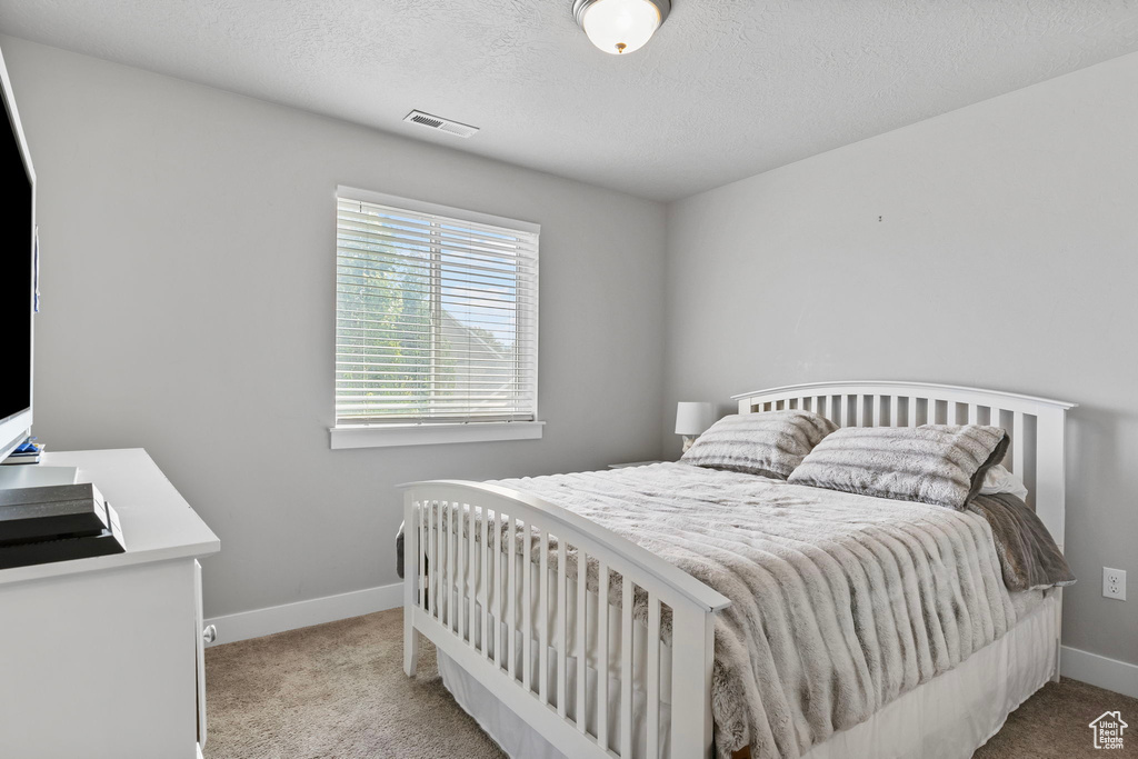 Bedroom featuring light colored carpet and a textured ceiling