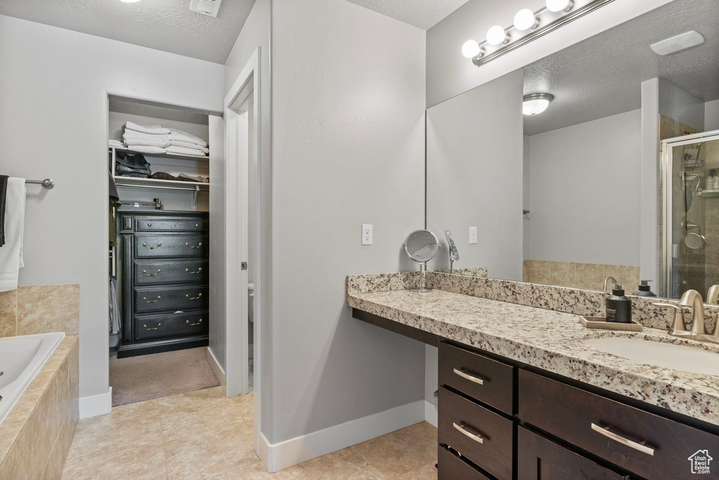 Bathroom featuring vanity, a textured ceiling, independent shower and bath, and tile patterned flooring