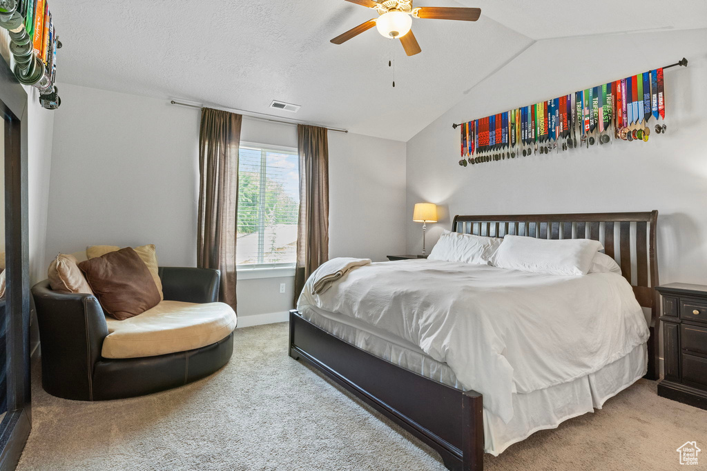 Carpeted bedroom featuring a textured ceiling, ceiling fan, and vaulted ceiling