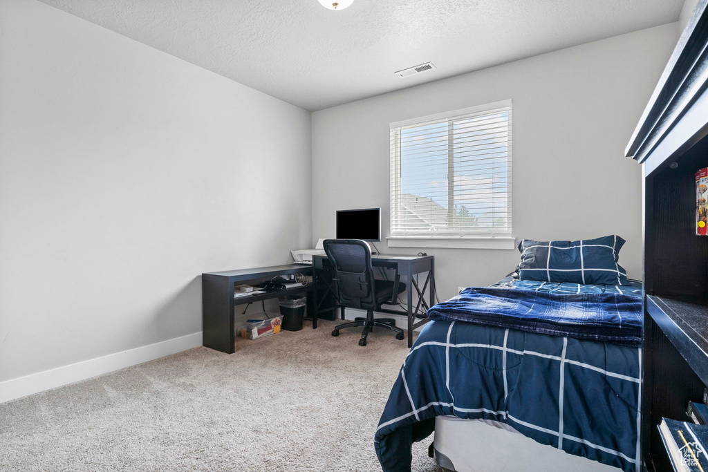 Bedroom with a textured ceiling and carpet