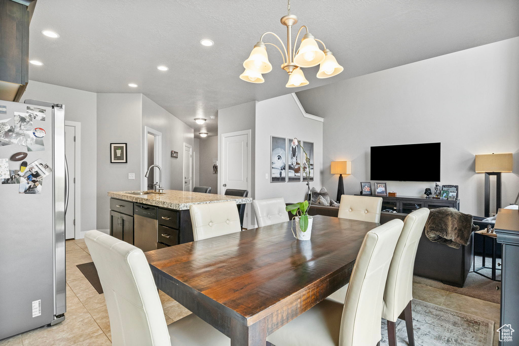 Tiled dining area with a textured ceiling, a notable chandelier, and sink