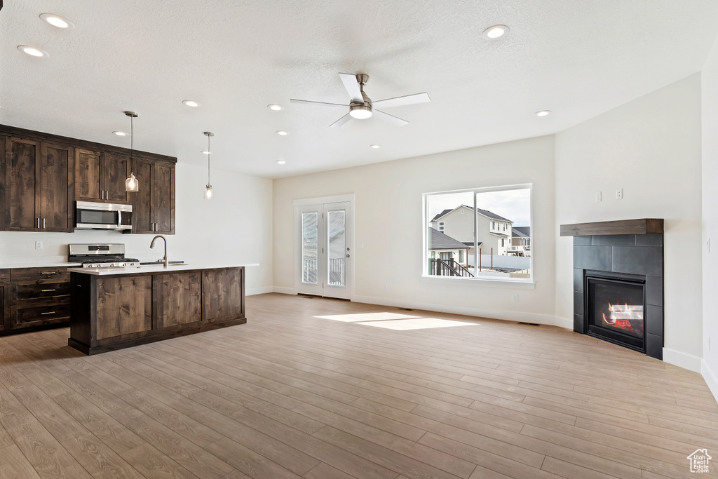 Kitchen featuring decorative light fixtures, appliances with stainless steel finishes, light wood-type flooring, and ceiling fan