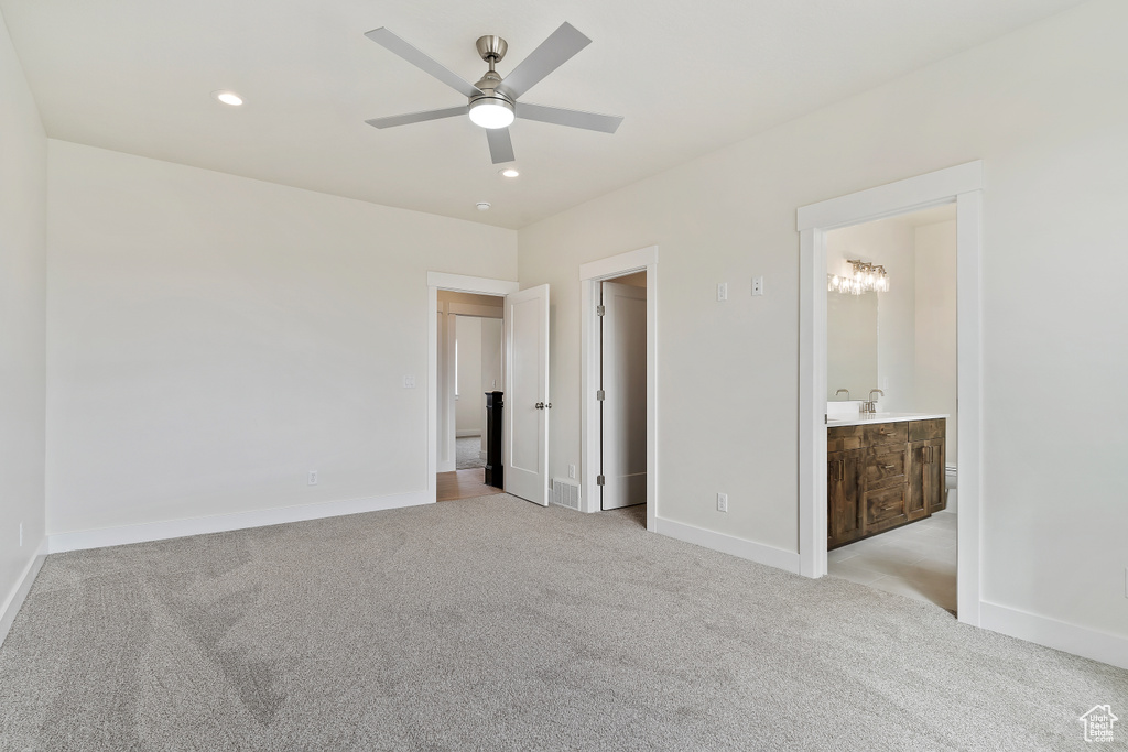 Unfurnished bedroom featuring connected bathroom, sink, light carpet, and ceiling fan