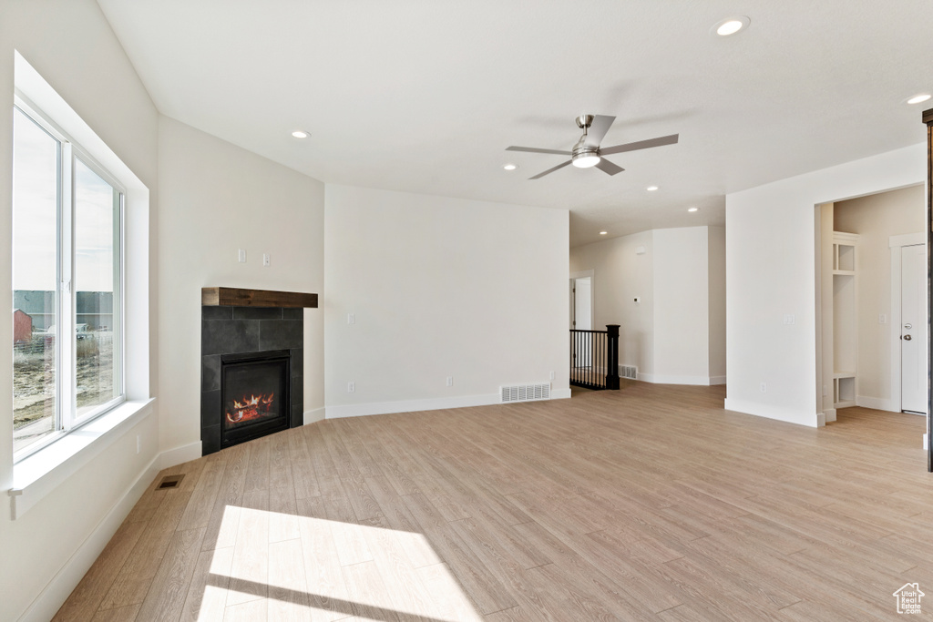 Unfurnished living room featuring a fireplace, light hardwood / wood-style flooring, and ceiling fan