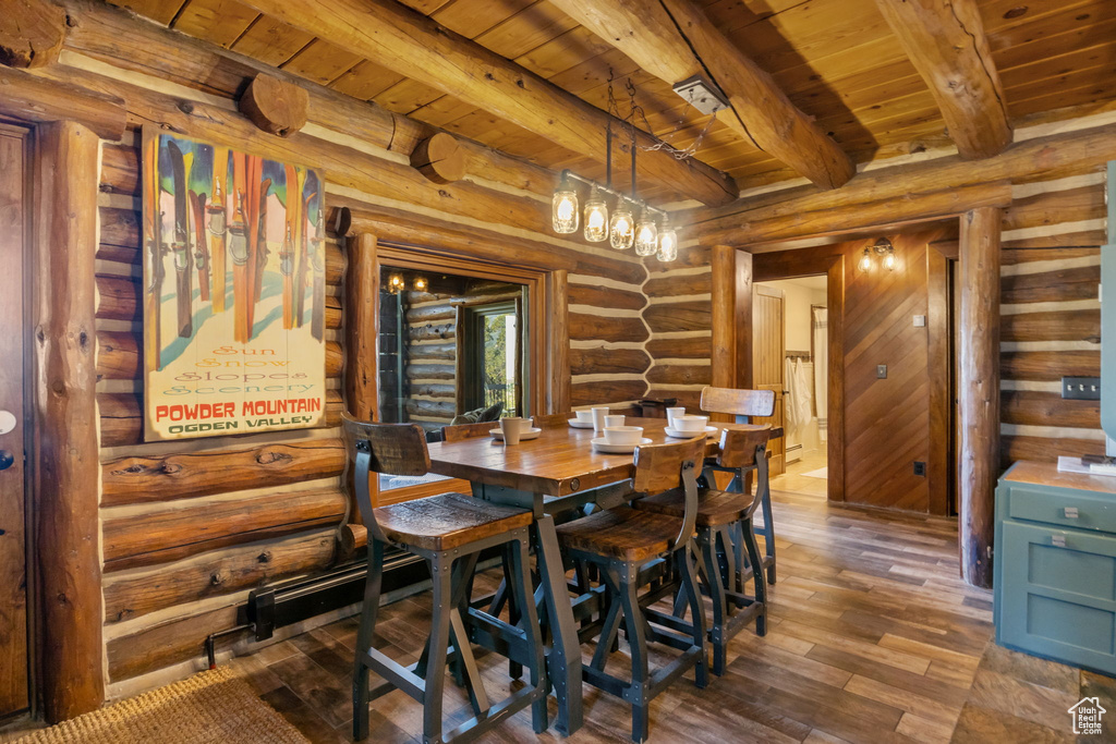 Dining area with wood ceiling, beamed ceiling, rustic walls, and dark hardwood / wood-style flooring