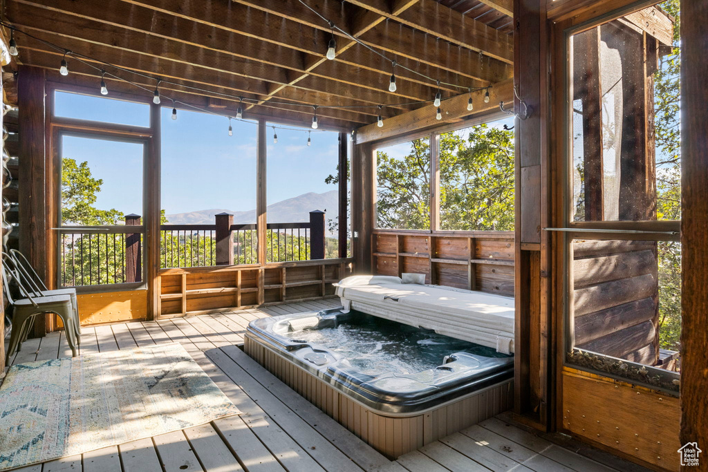 Sunroom / solarium with a healthy amount of sunlight, a mountain view, and a hot tub