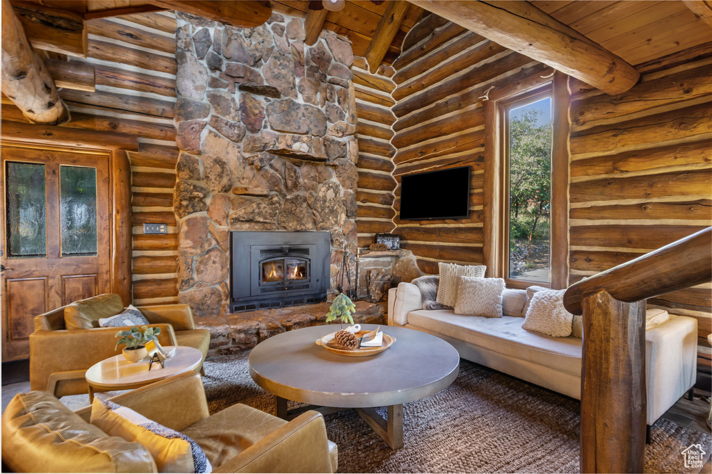 Living room with wood ceiling, log walls, and a stone fireplace