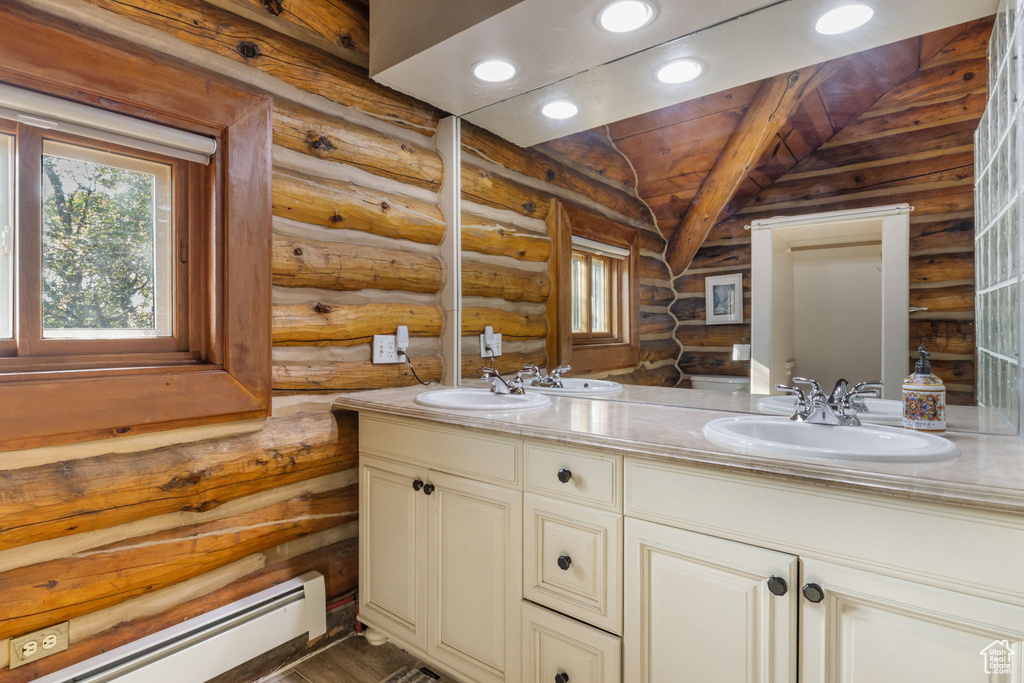 Bathroom with lofted ceiling, vanity, baseboard heating, and rustic walls