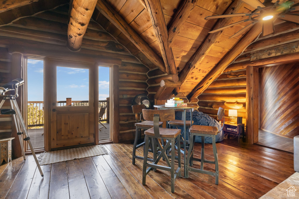 Dining room with lofted ceiling with beams, hardwood / wood-style floors, log walls, and wood ceiling