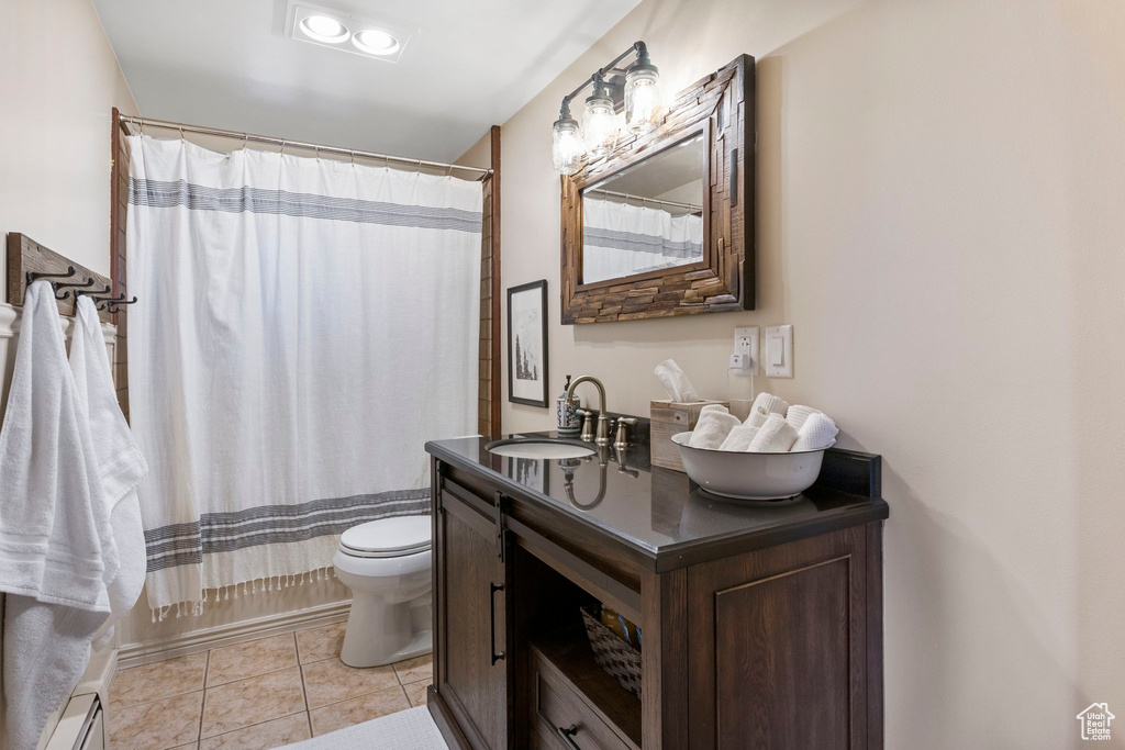 Full bathroom featuring toilet, tile patterned floors, vanity, a baseboard radiator, and shower / bath combination with curtain