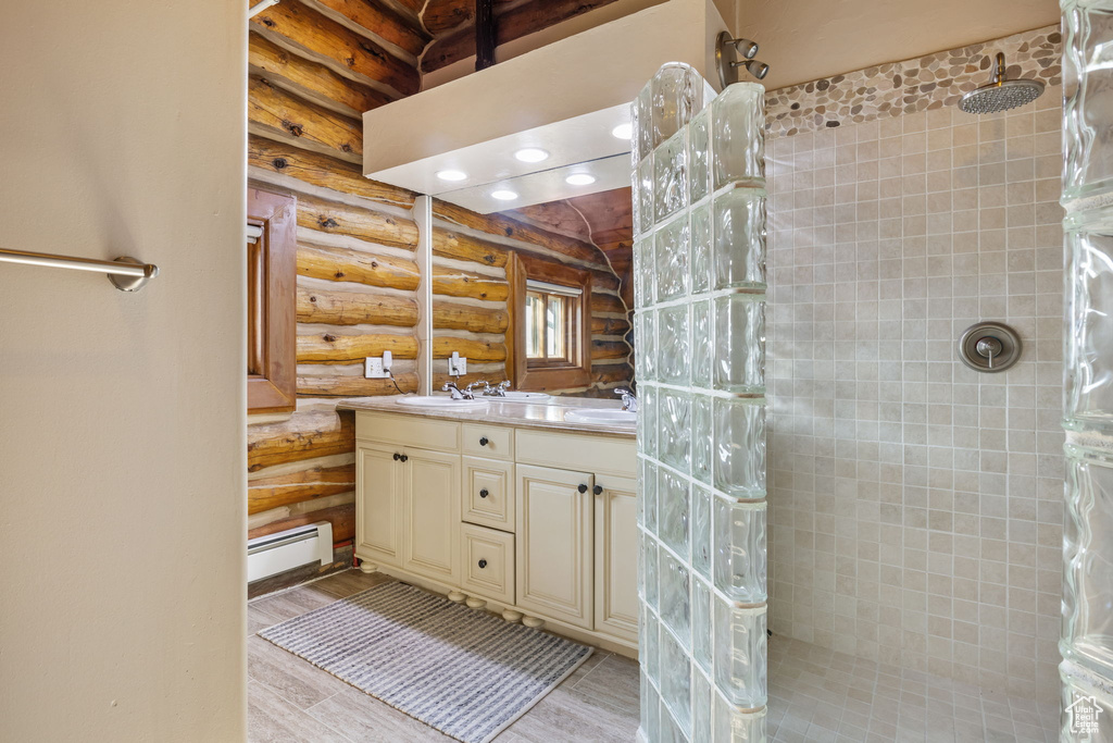 Bathroom with log walls, hardwood / wood-style flooring, tiled shower, and vanity