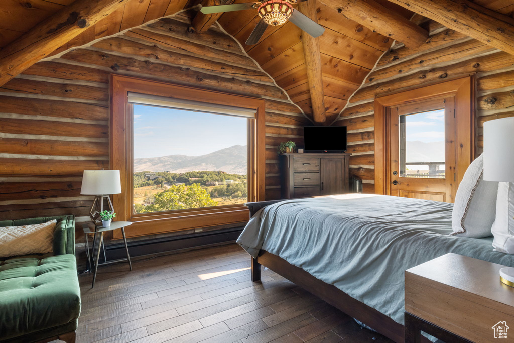 Bedroom featuring dark wood-type flooring, vaulted ceiling with beams, rustic walls, and multiple windows