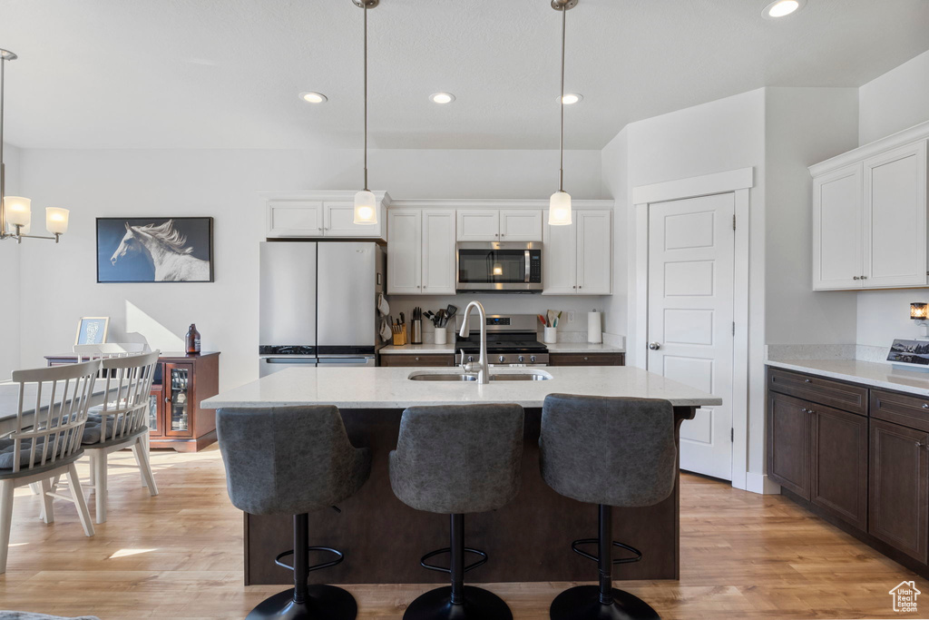 Kitchen featuring pendant lighting, white cabinetry, sink, appliances with stainless steel finishes, and light hardwood / wood-style floors