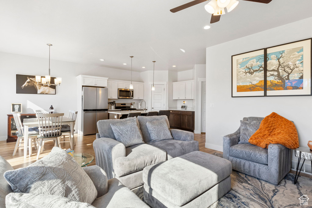 Living room featuring sink, ceiling fan with notable chandelier, and hardwood / wood-style flooring