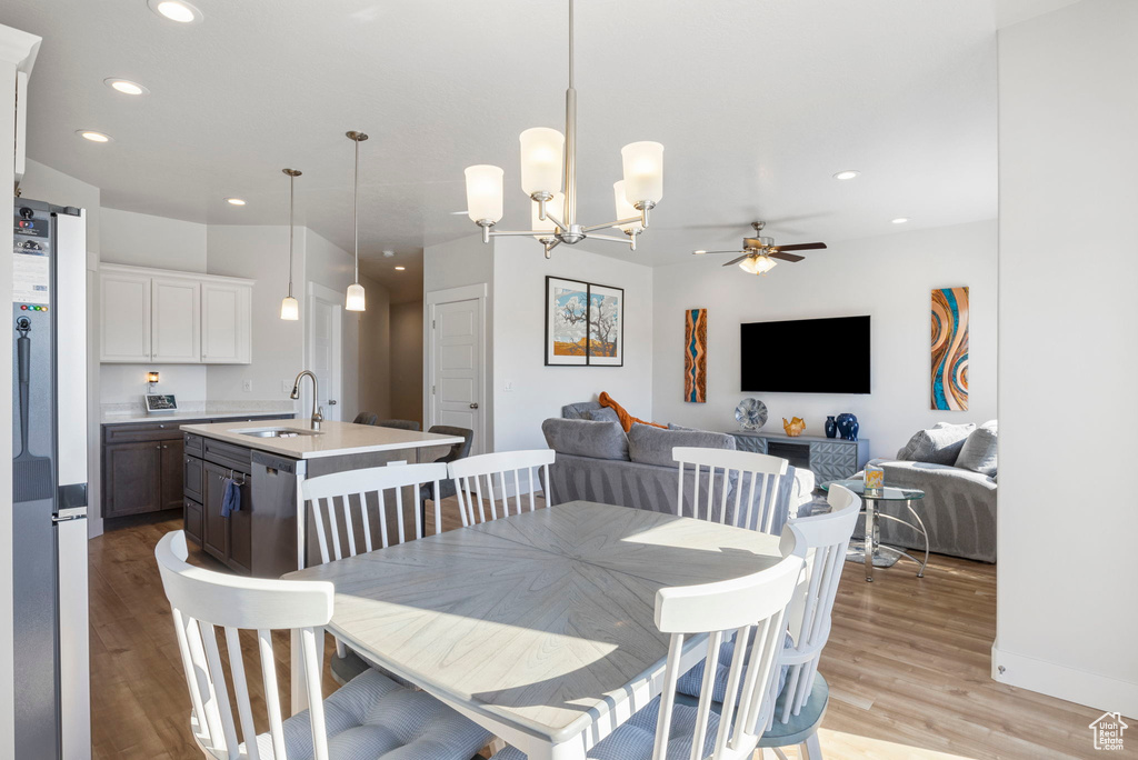 Dining space featuring light hardwood / wood-style flooring, ceiling fan with notable chandelier, and sink