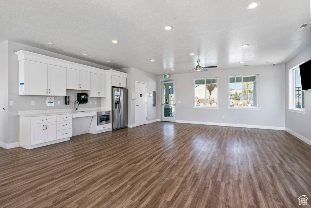 Unfurnished living room featuring a textured ceiling, ceiling fan, sink, and dark hardwood / wood-style floors