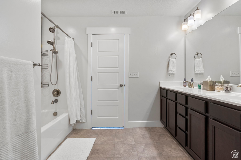 Bathroom featuring tile patterned flooring, shower / bath combo with shower curtain, and vanity