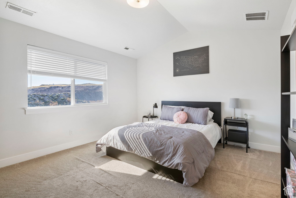 Bedroom with vaulted ceiling and light colored carpet