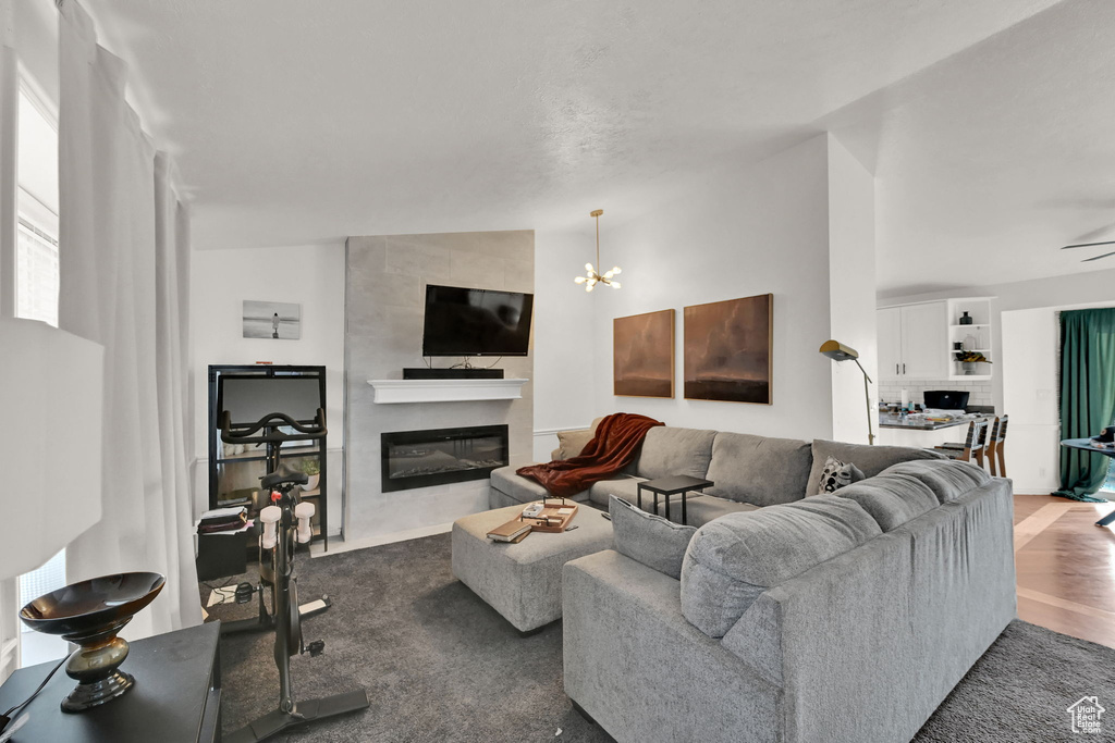 Living room with lofted ceiling, ceiling fan with notable chandelier, dark hardwood / wood-style flooring, and a fireplace