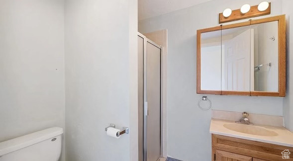 Bathroom with vanity, toilet, and a shower with shower door