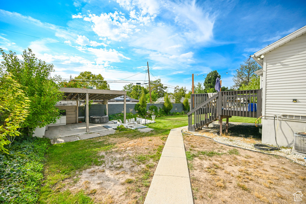 View of yard with a wooden deck, central AC unit, and a patio area