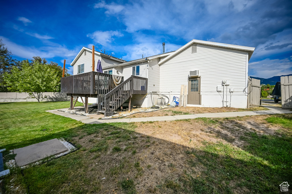 Back of house with a wooden deck and a yard