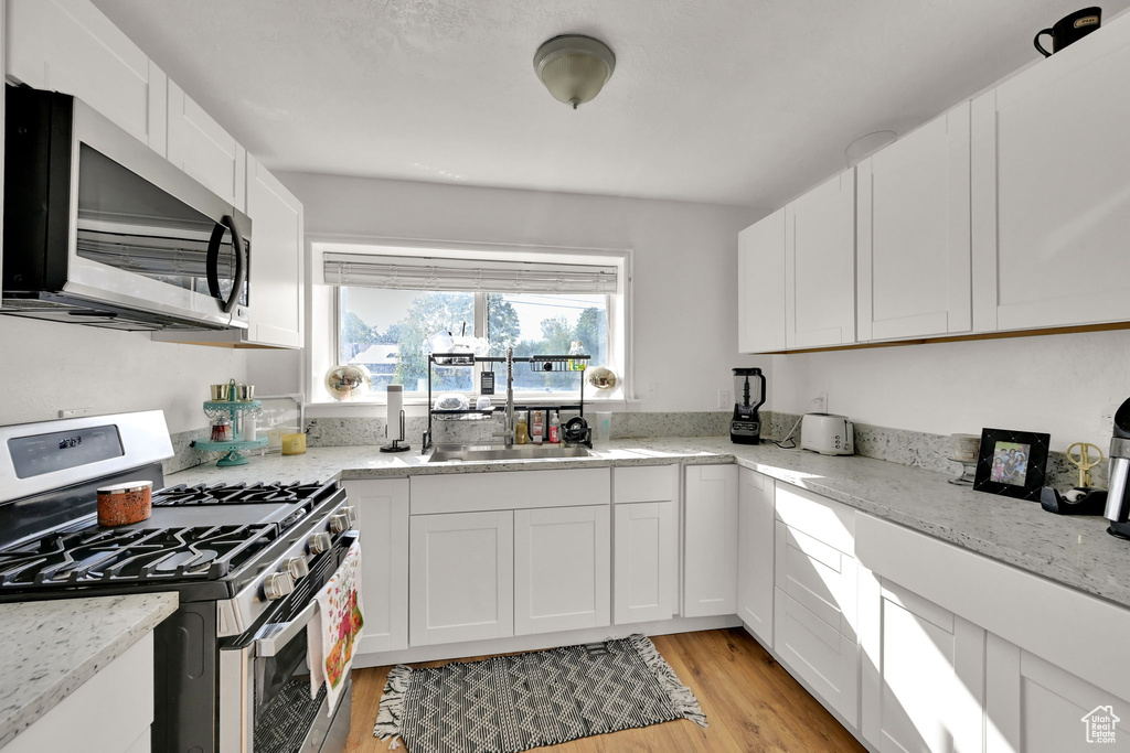 Kitchen featuring stainless steel appliances, light hardwood / wood-style floors, and white cabinetry