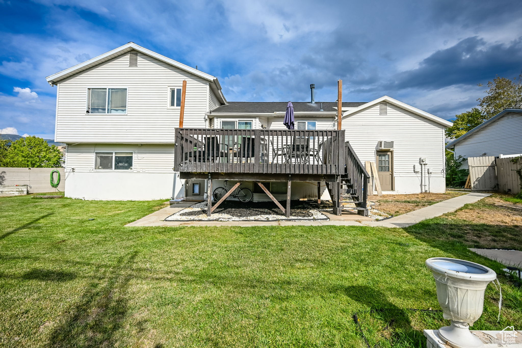 Back of house with a lawn and a deck