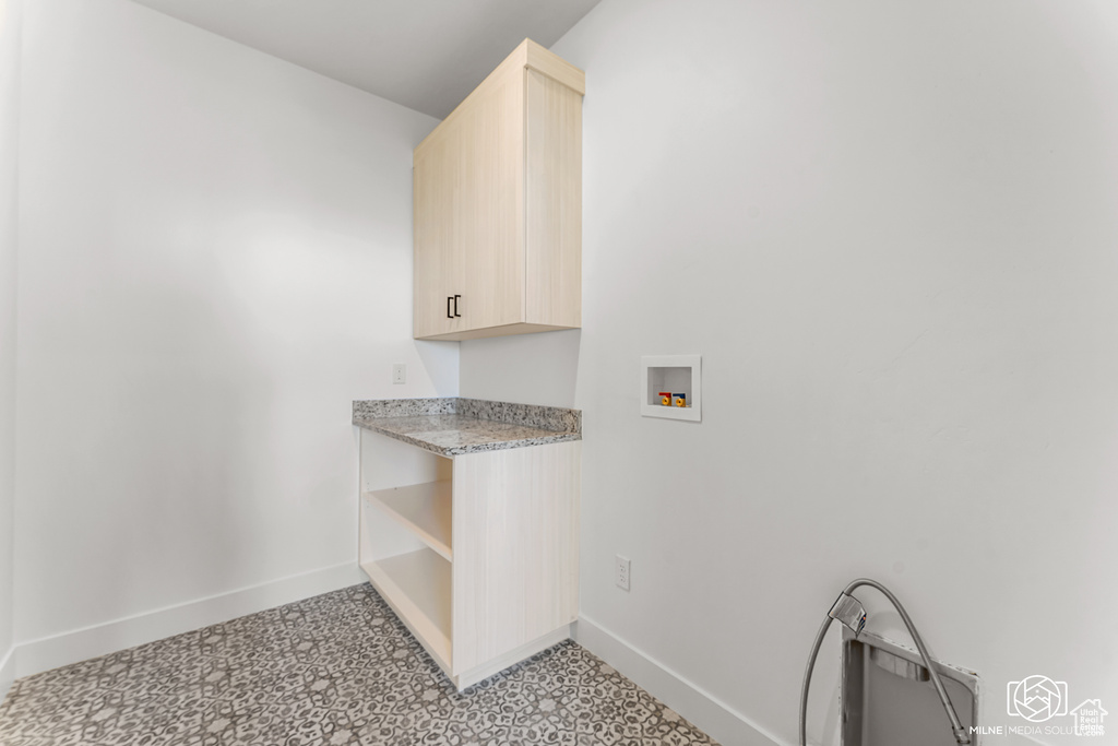 Clothes washing area featuring hookup for a washing machine and cabinets