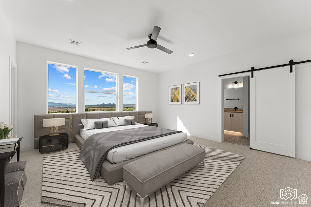 Bedroom with a barn door, light carpet, ceiling fan, and ensuite bathroom