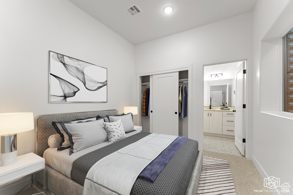 Bedroom featuring light colored carpet, ensuite bathroom, and a closet