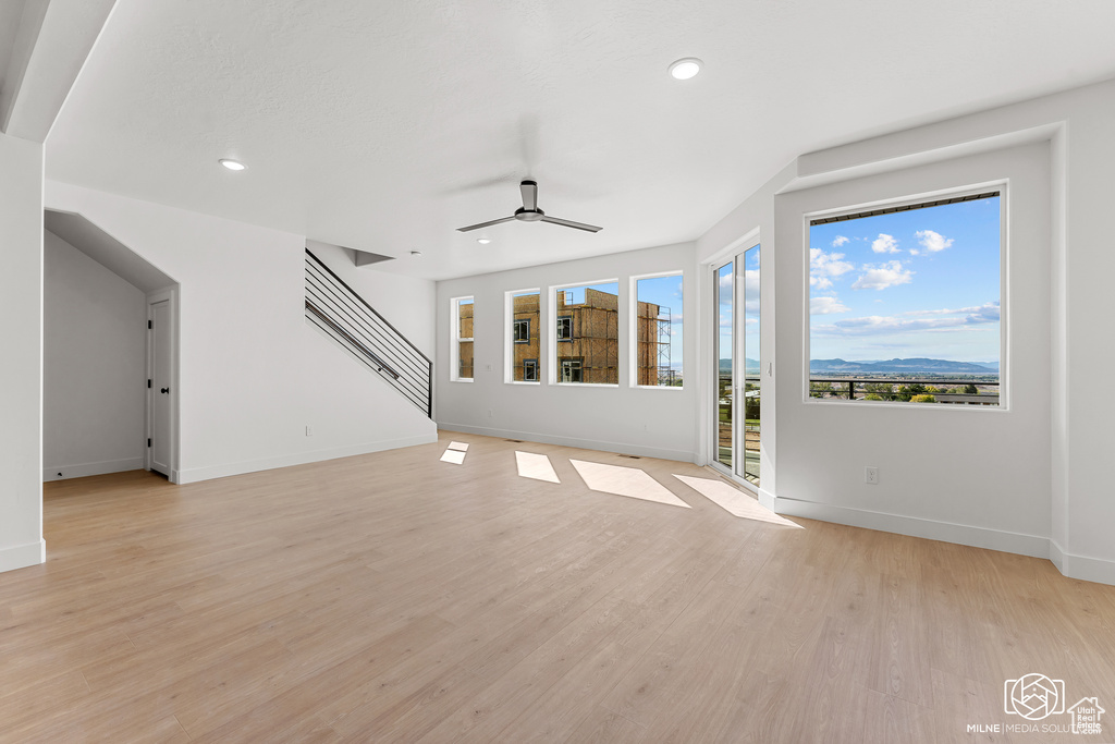 Unfurnished living room with ceiling fan and light wood-type flooring