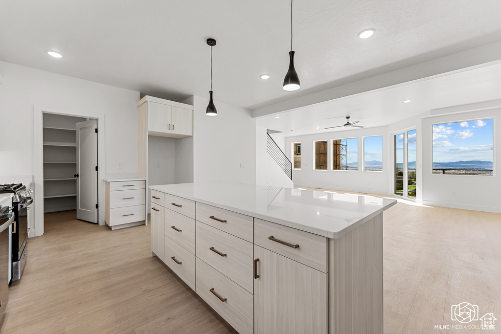 Kitchen featuring ceiling fan, decorative light fixtures, light hardwood / wood-style flooring, white cabinetry, and stainless steel gas range oven