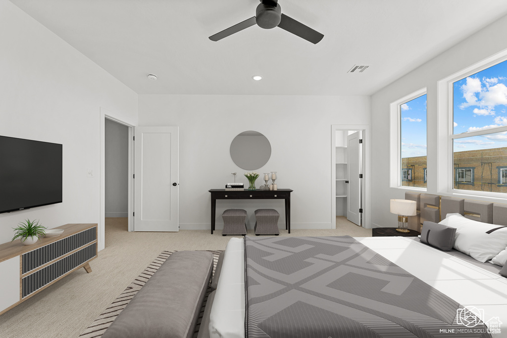 Carpeted bedroom with ceiling fan and a walk in closet