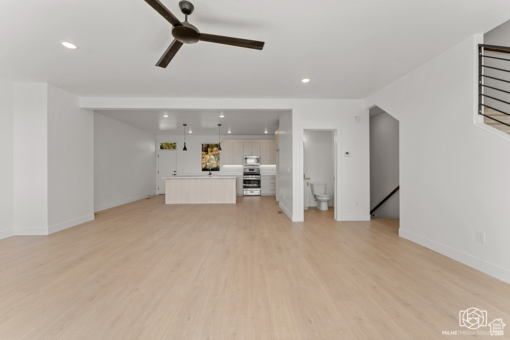 Unfurnished living room with light wood-type flooring, ceiling fan, and sink