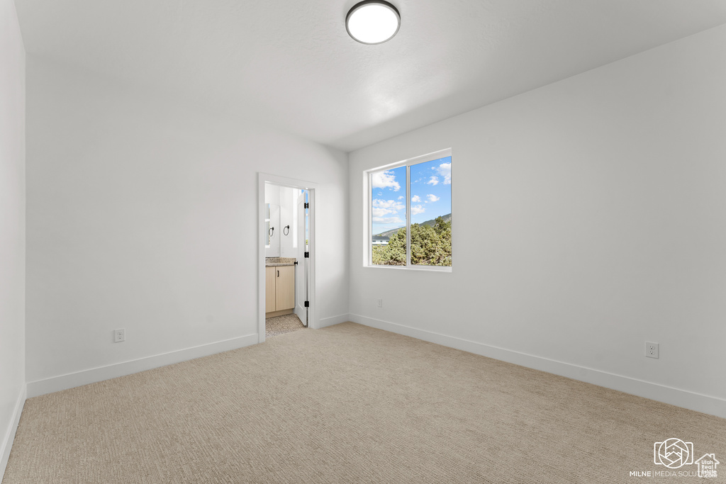 Unfurnished bedroom with light colored carpet and ensuite bathroom