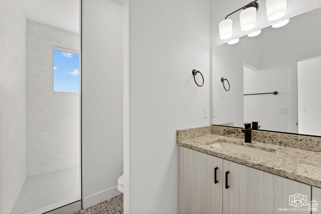 Bathroom with vanity, toilet, and tiled shower