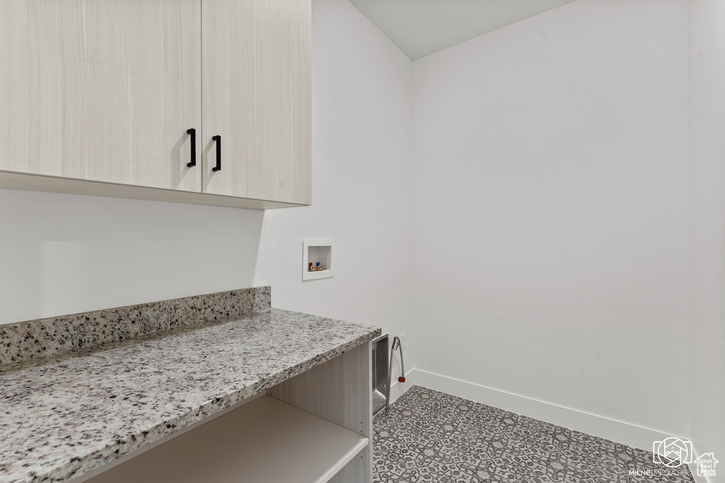 Washroom featuring hookup for a washing machine, cabinets, and tile patterned floors