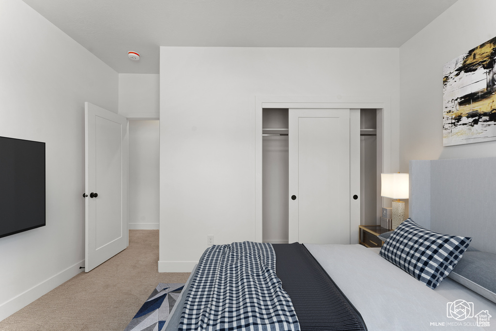 Bedroom with light carpet and a closet