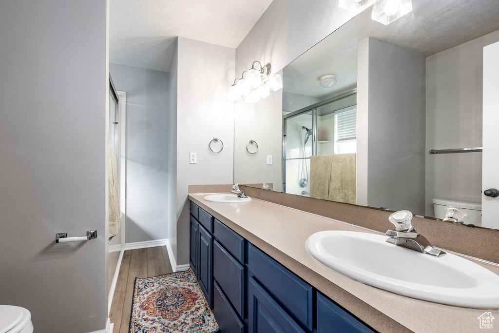 Bathroom with a shower with door, vanity, toilet, and hardwood / wood-style flooring