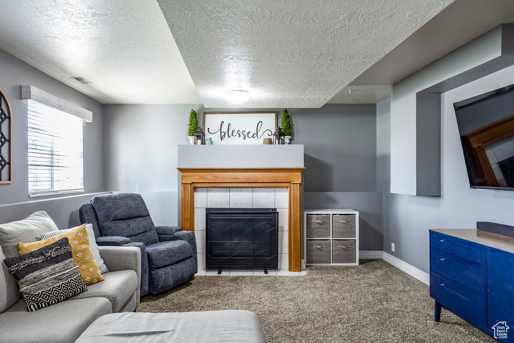 Carpeted living room featuring a fireplace and a textured ceiling