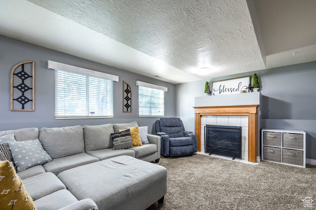 Living room featuring a textured ceiling, carpet, and a tile fireplace